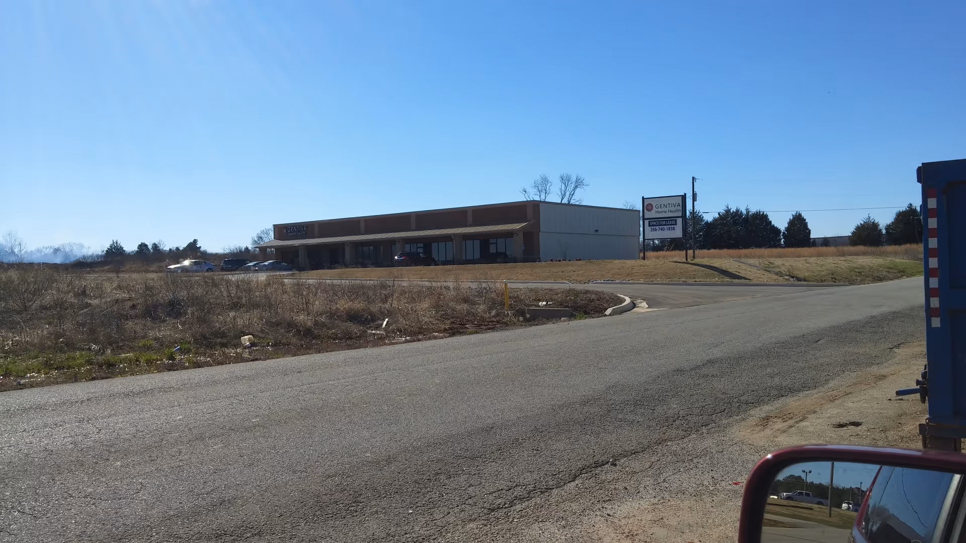 Single-story facility along a rural road with Gentiva Home Health sign.