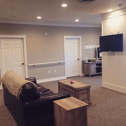 Cozy living room lounge with leather sofa, coffee tables, wall-mounted TV and neutral walls