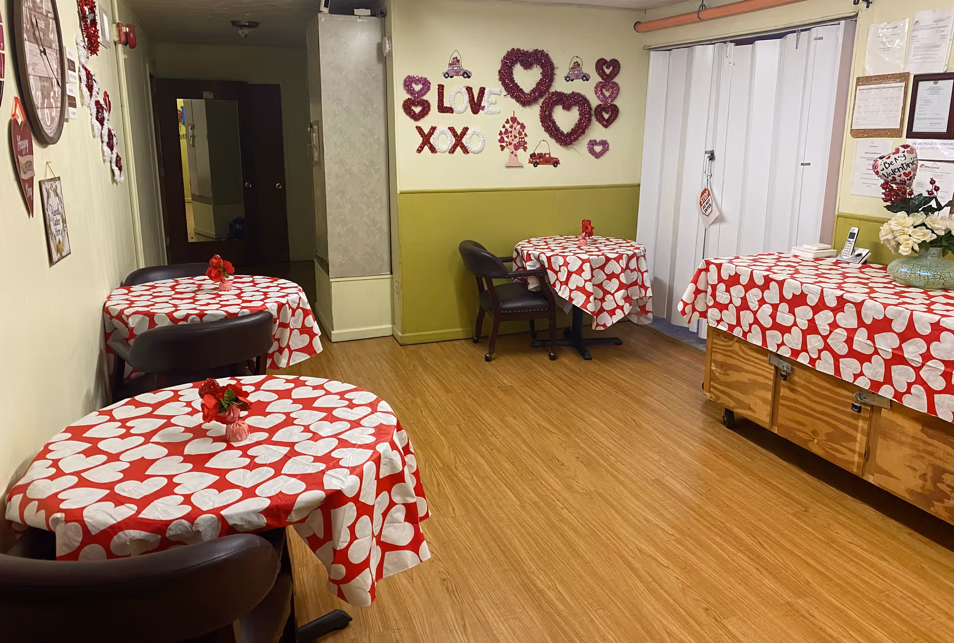 Valentine-themed dining area with round tables covered in red heart cloths.