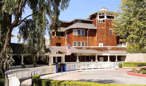 Brick senior living facility with a porte-cochère entrance and surrounding trees.