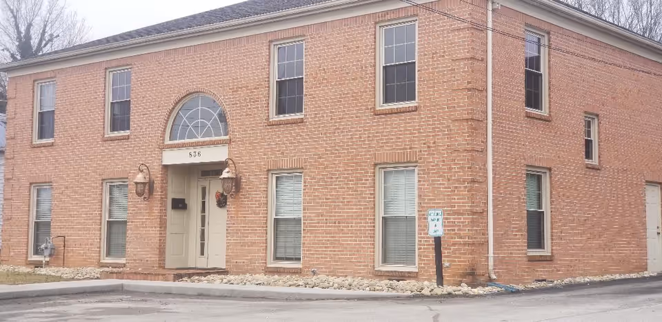 Brick front of a two-story facility with arched window above entrance and lanterns.