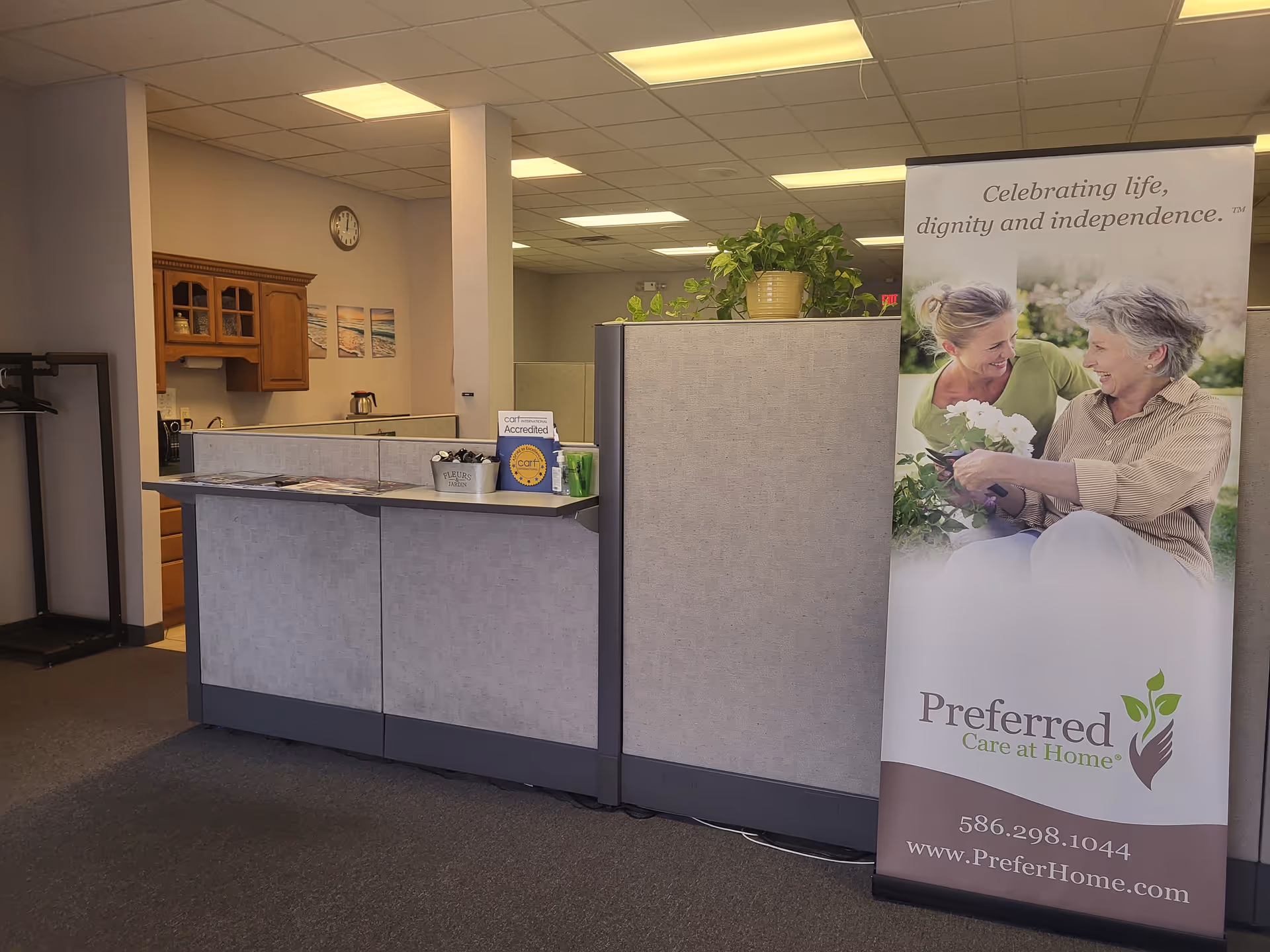 Reception desk area inside a senior care office with a banner and plants.