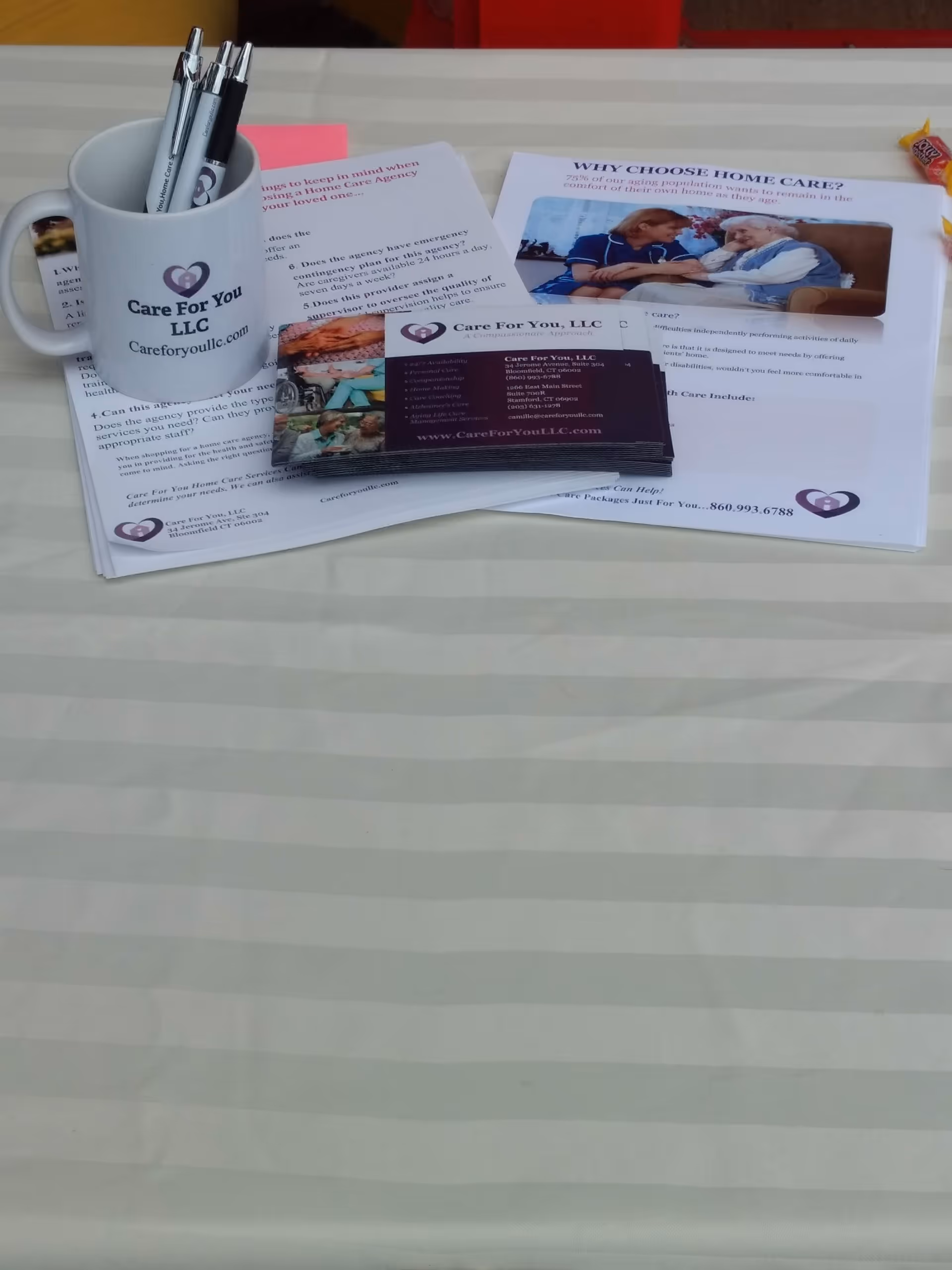 A Care For You LLC mug and brochures displayed on a striped table.
