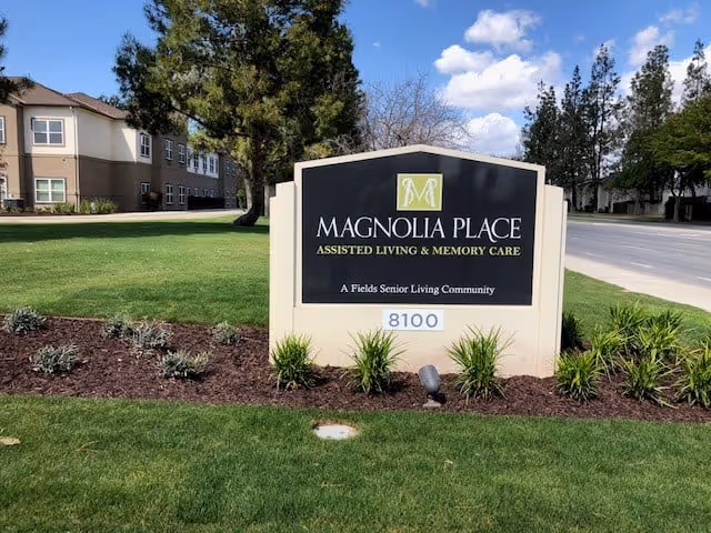Front view of Magnolia Place sign with manicured lawn and surrounding trees
