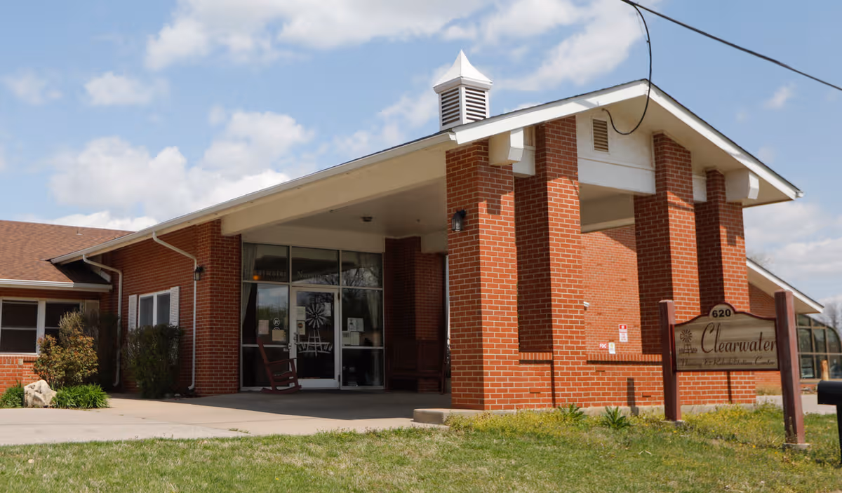 Brick senior living facility entrance with glass doors and a Clearwater sign