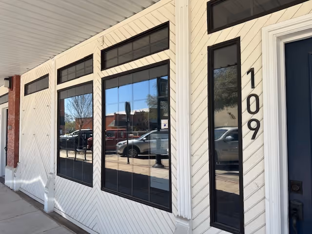 White siding building with tall windows and a blue door, numbered 109