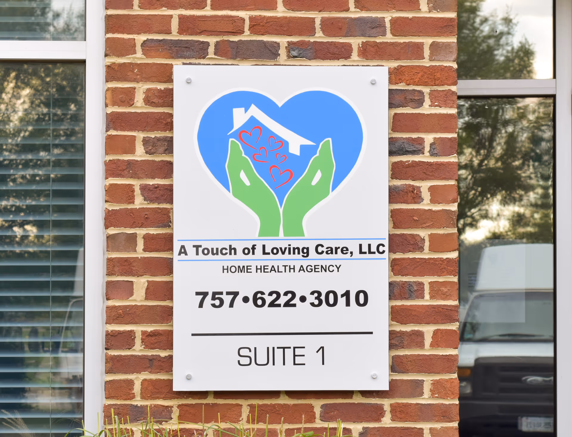 Exterior brick wall with a large sign for A Touch of Loving Care, LLC.