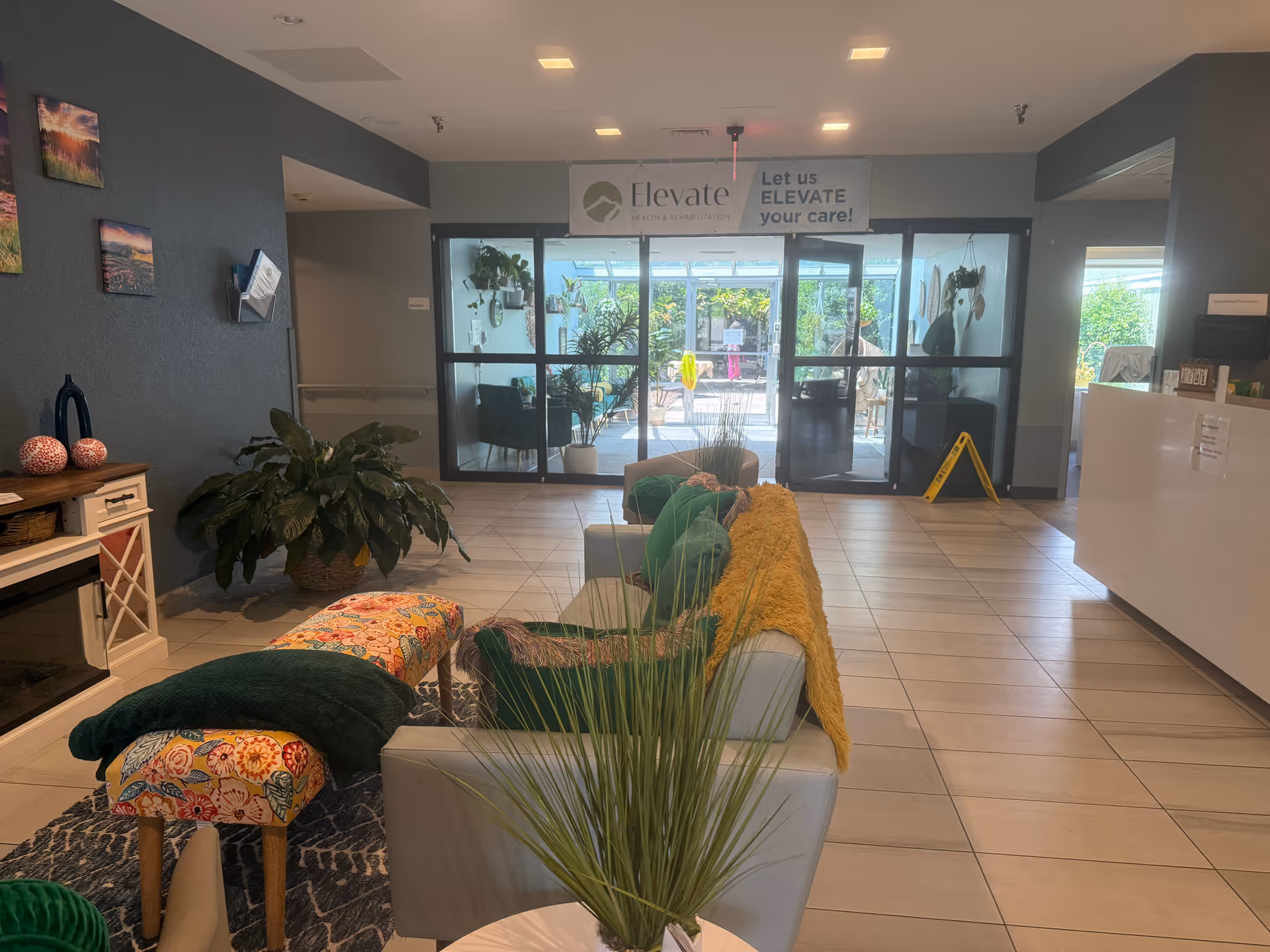 Lobby seating area with couches, plants, and glass entry doors inside Asheville Nursing & Rehabilitation Center