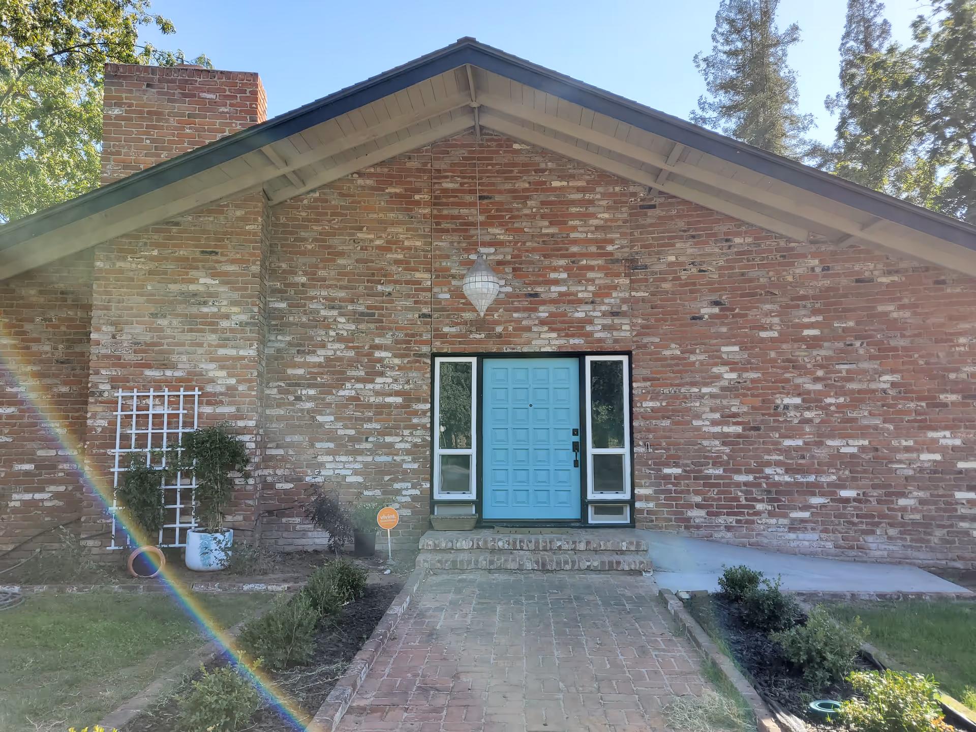 Brick exterior of Oxford Manor RCFE with a bright blue front door and landscaped path.
