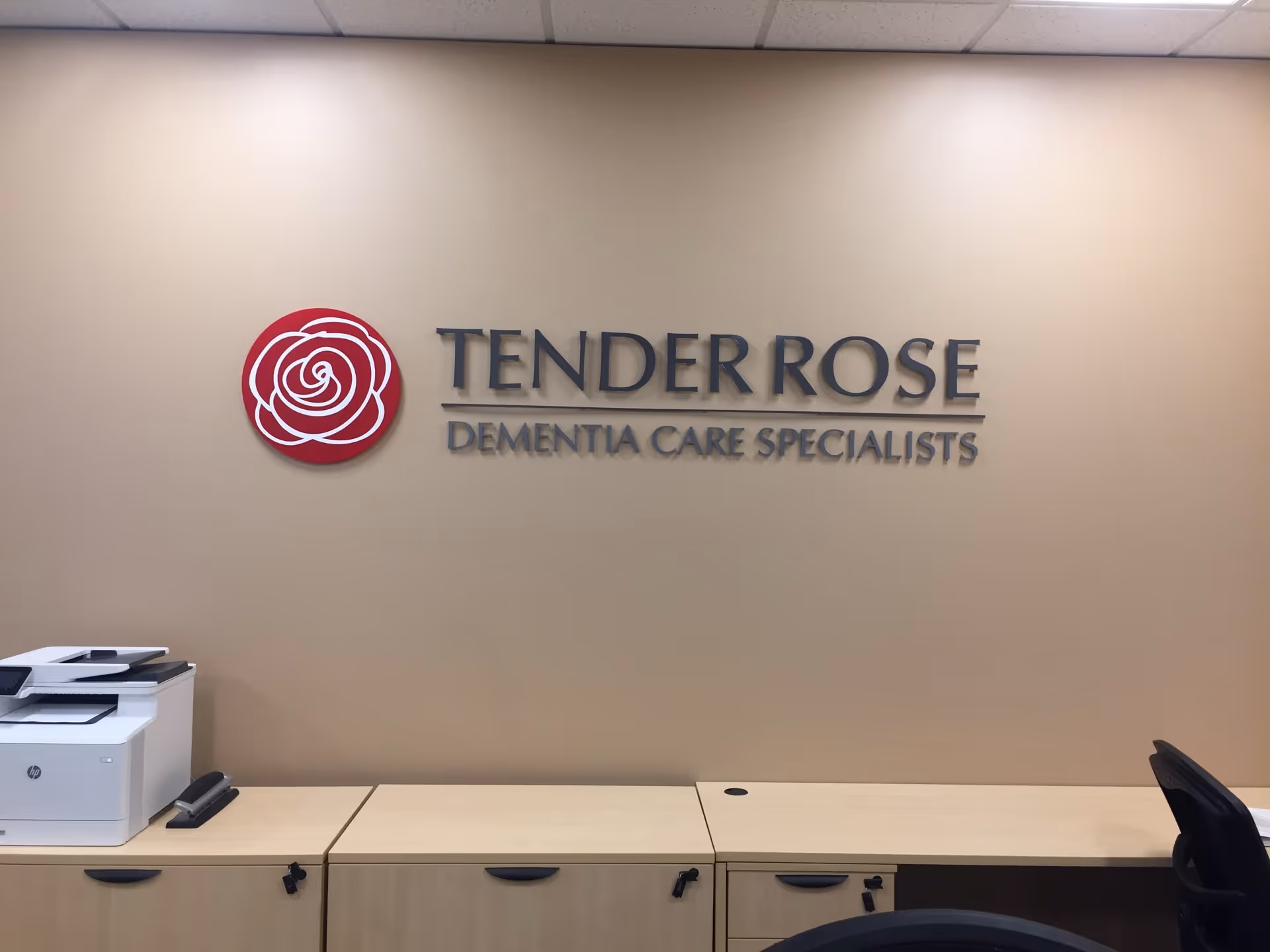 Reception area with beige wall, Tender Rose sign, and desk under ceiling tiles