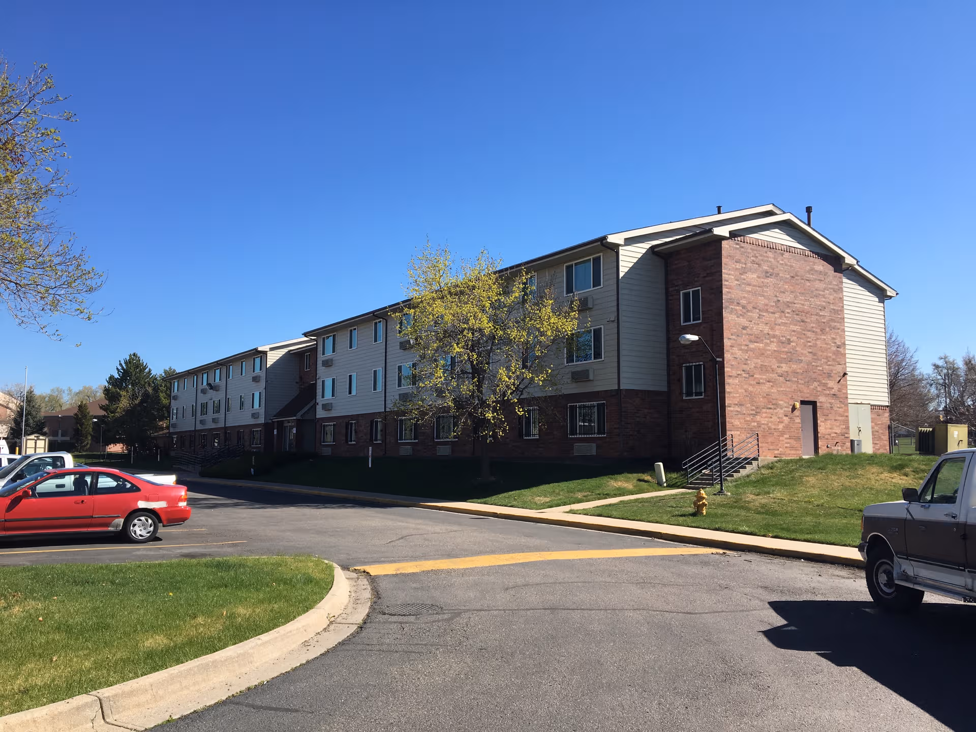 Exterior view of Allen Gardens senior living building with brick facade and parking lot.