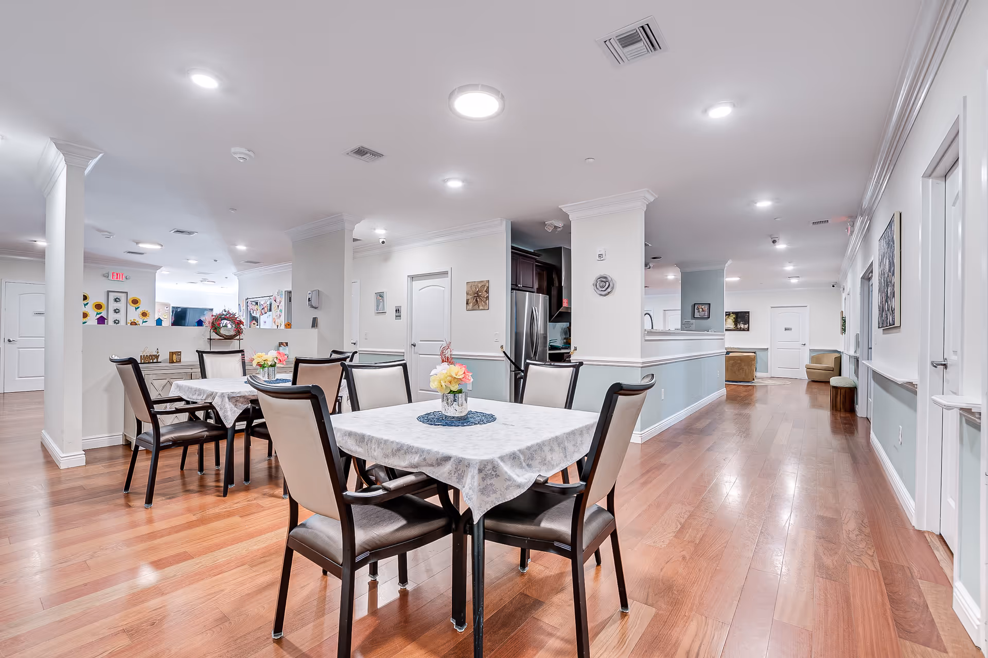 Bright dining room at Peaceful Pines Residence Memory Care Community with tables, chairs, and hardwood floors.