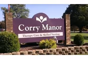 Purple Corry Manor sign with brick pillars and landscaped entrance at the facility front.