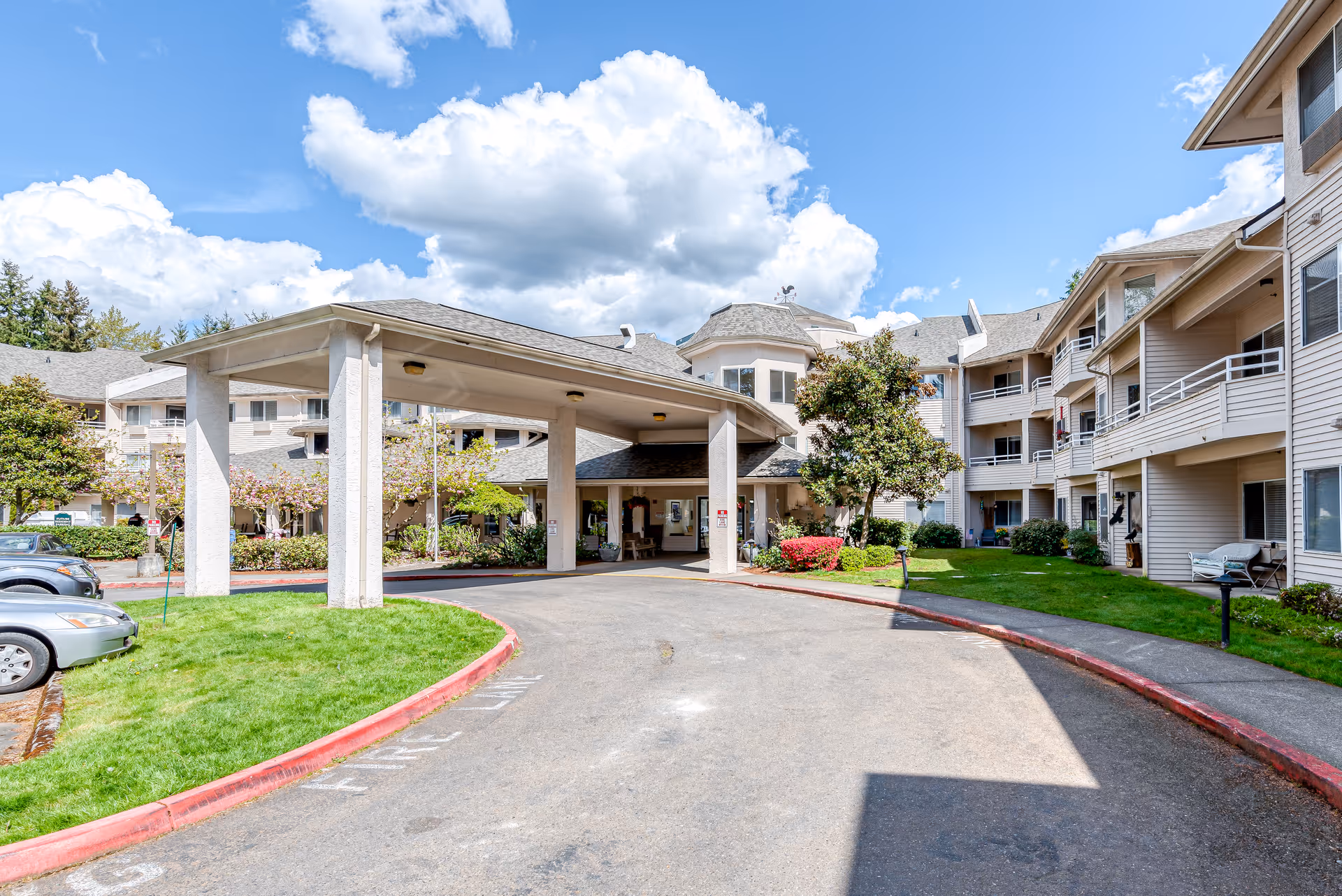 Exterior view of a senior living campus with a covered entrance and landscaped grounds.