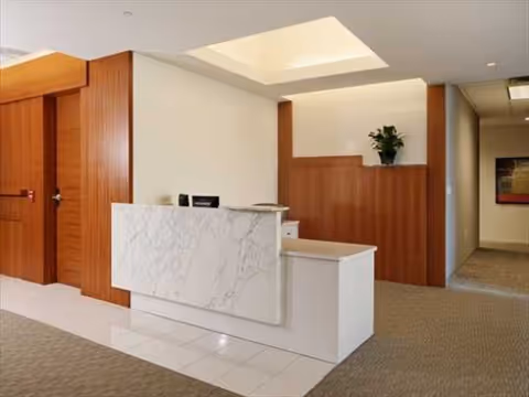 A reception desk with a marble counter sits in a modern senior living facility lobby.