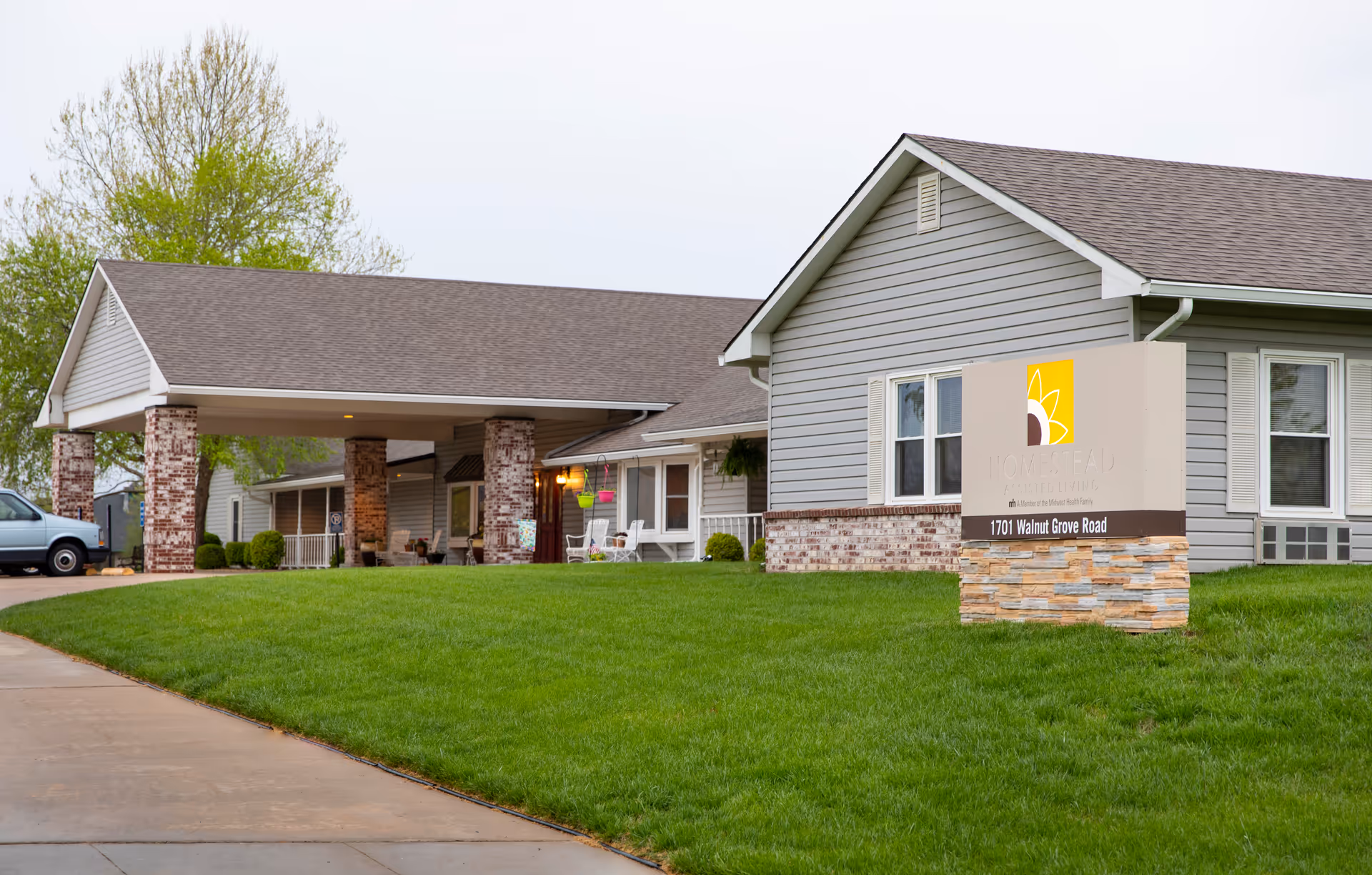 Front exterior of Homestead Assisted Living Derby with entry columns, sign, and green lawn.
