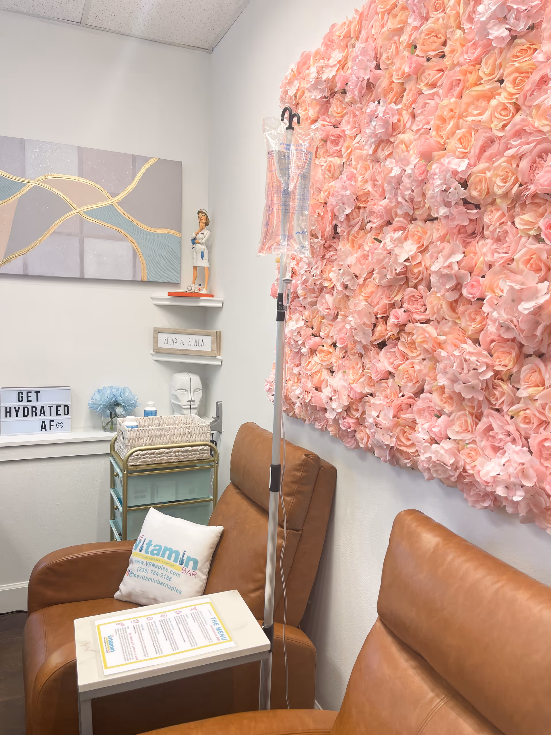 Cozy interior corner with pink floral wall, leather chairs, and an IV stand.