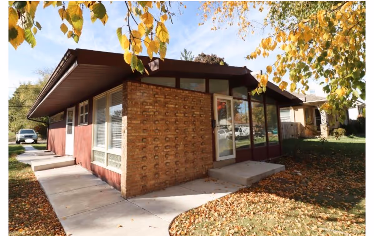 Brick exterior of an assisted living facility with glass entry doors and fallen leaves.