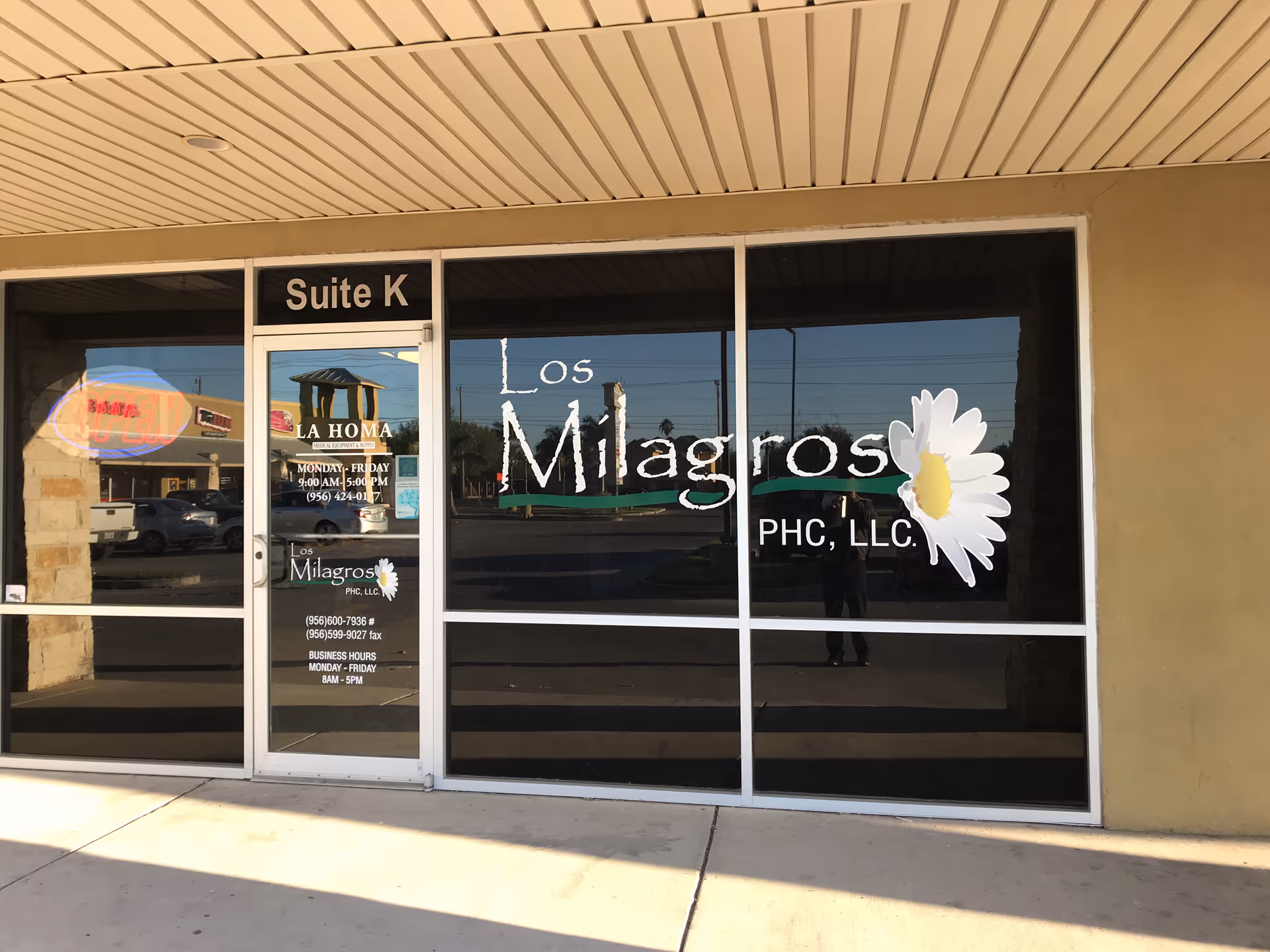 Exterior storefront windows display 'Los Milagros PHC LLC' with a daisies logo.