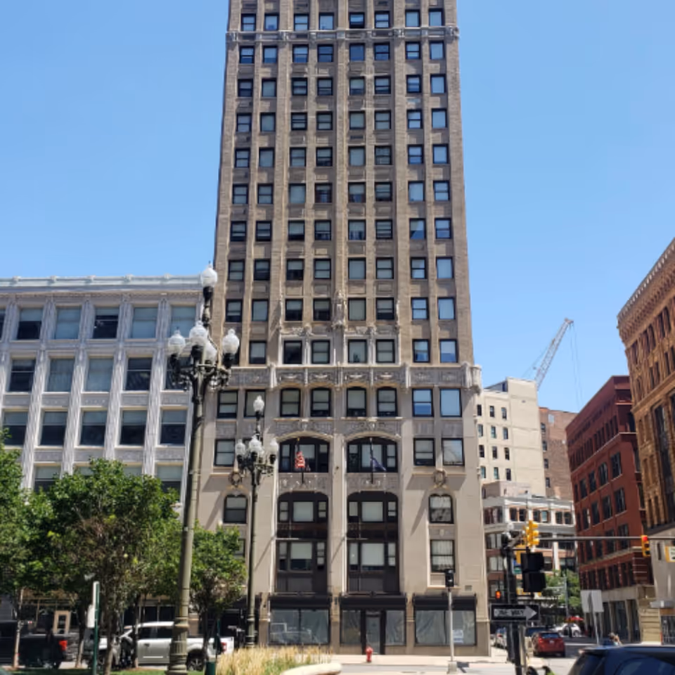 Tall brown brick apartment building on a city street with a vintage lamppost