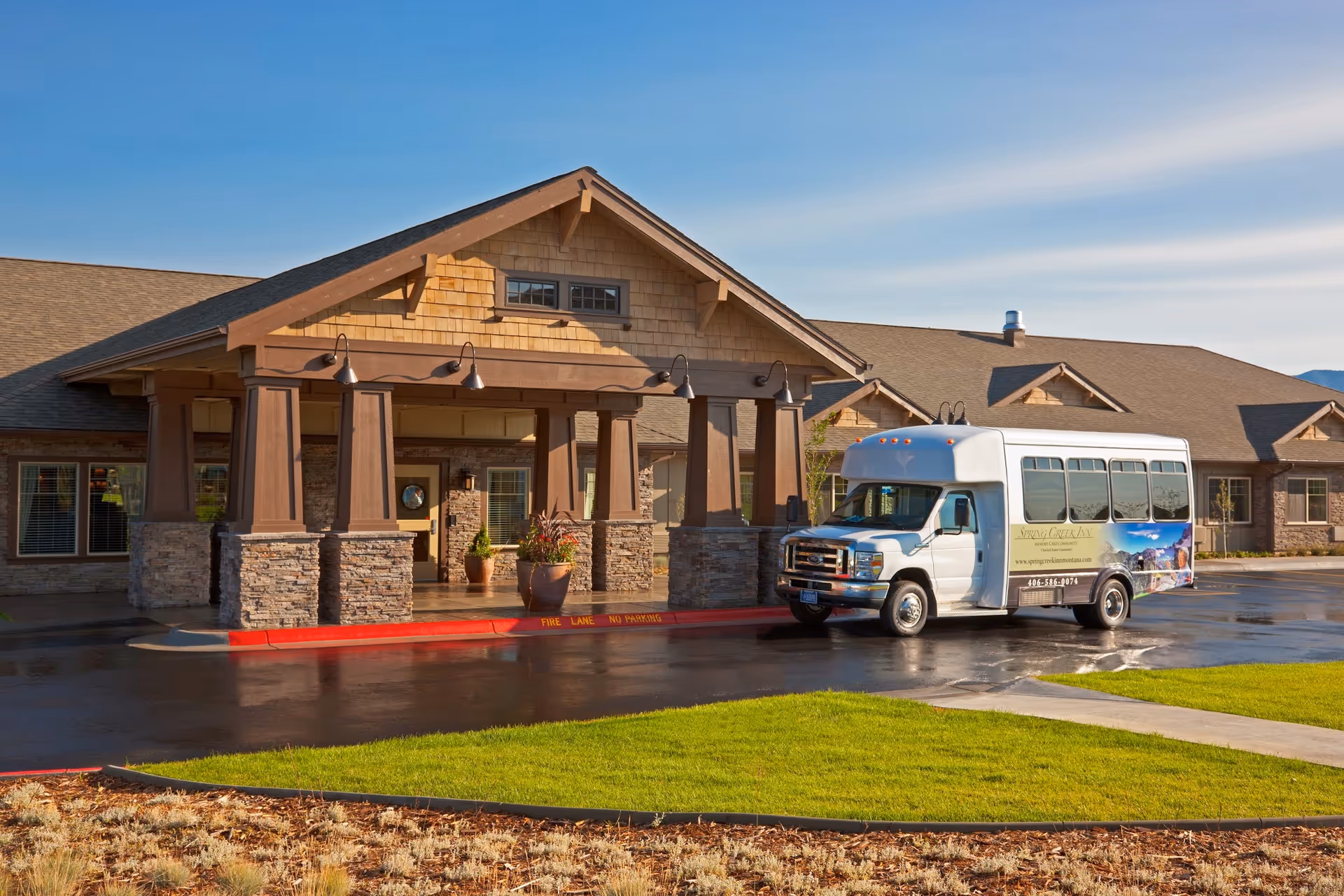 Front view of Spring Creek Inn Memory Care Community with a bus parked at the entrance.