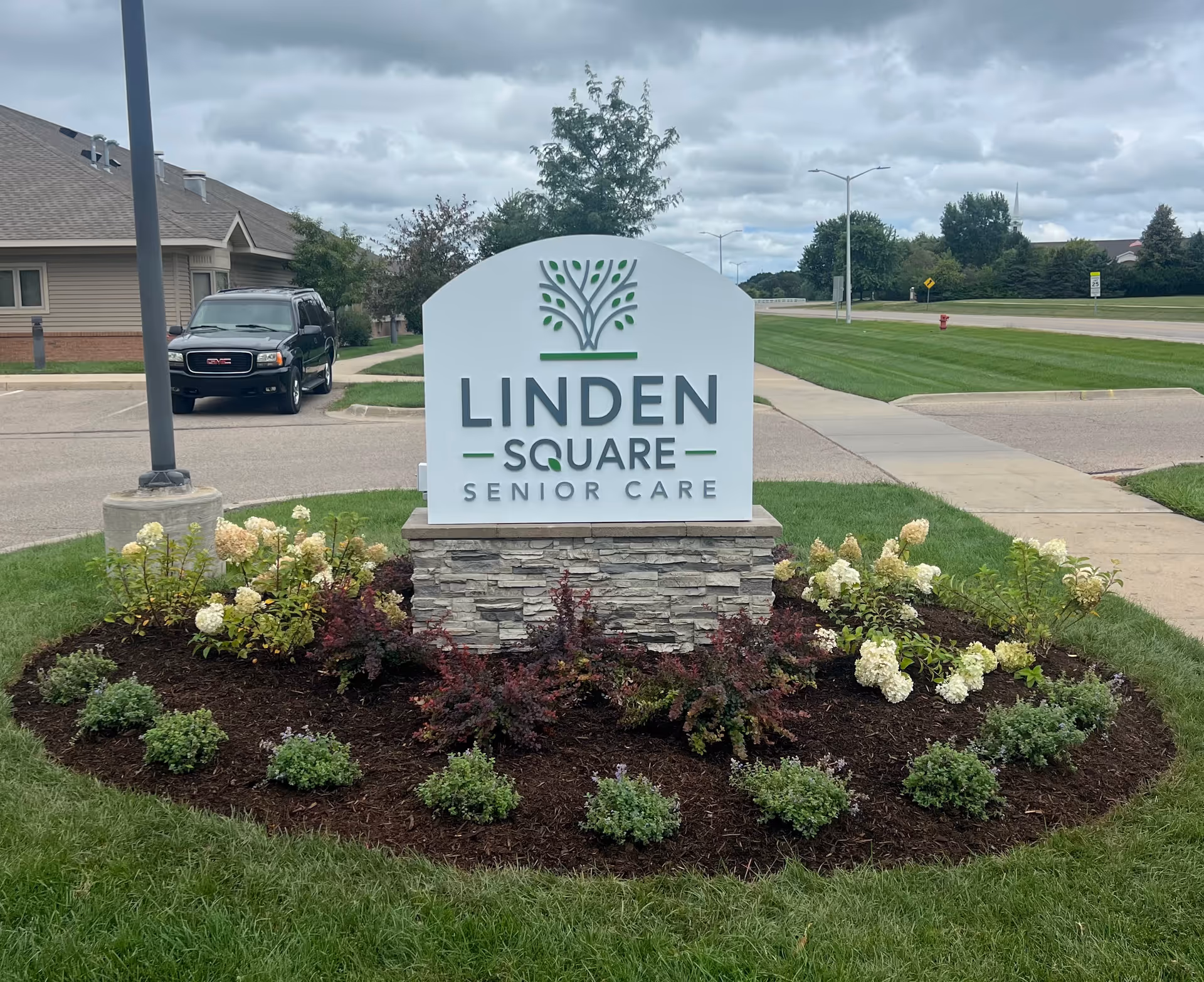 Exterior view of Linden Square Senior Care sign surrounded by a landscaped flower bed.
