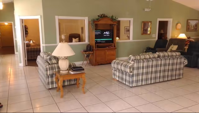 A spacious living room in an assisted living facility with plaid sofas and a TV.