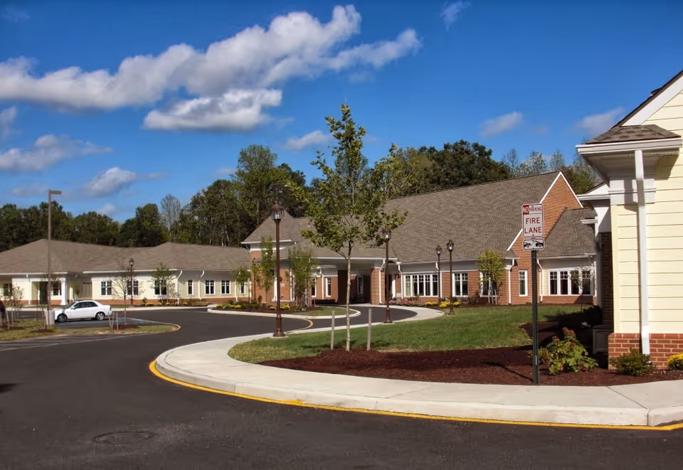 Exterior view of a single-story senior living facility with a curved driveway and landscaping.