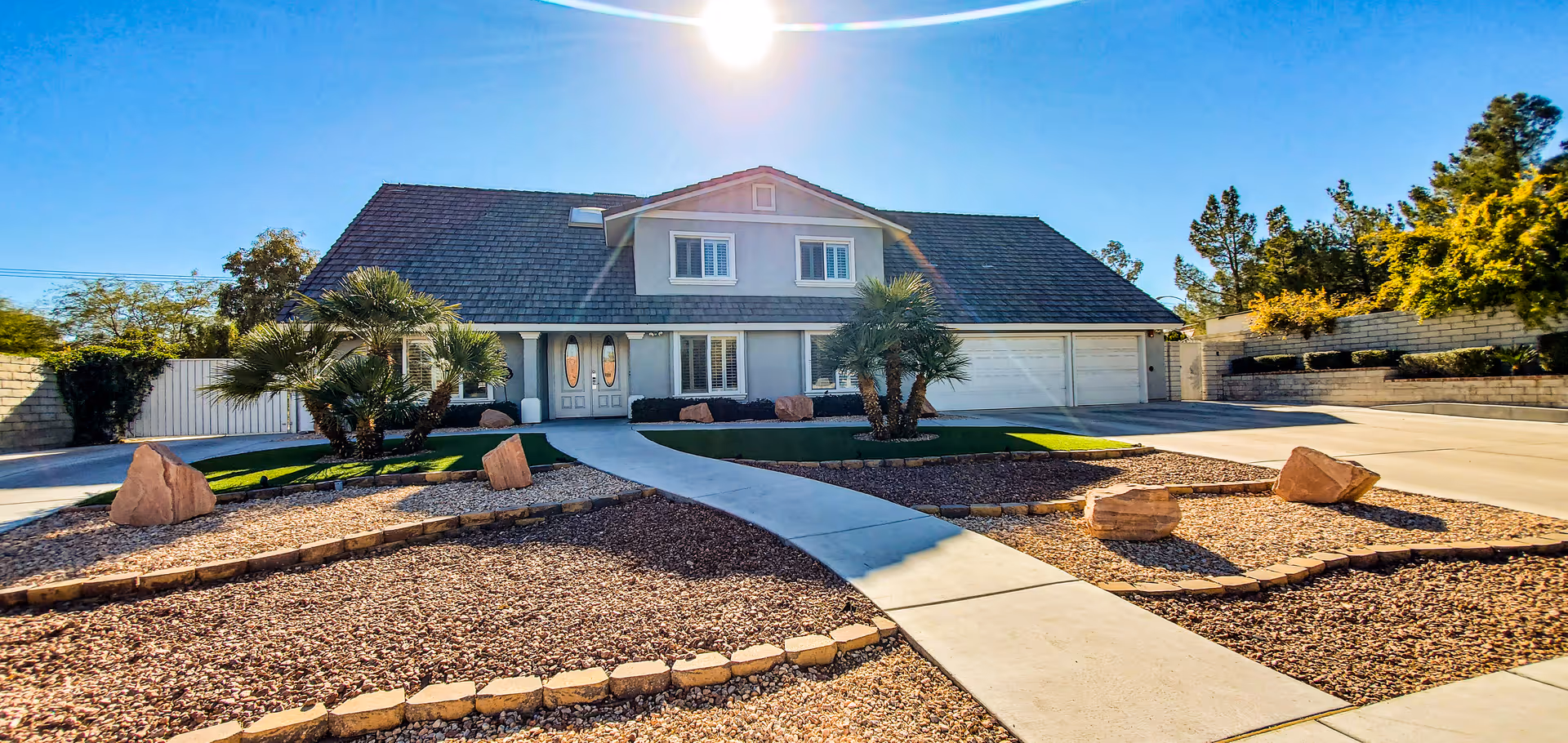 Sunlit front of a memory care facility with a curved walkway and desert landscaping.