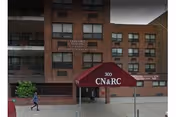 Brick nursing facility facade with CN&RC canopy and people near entrance