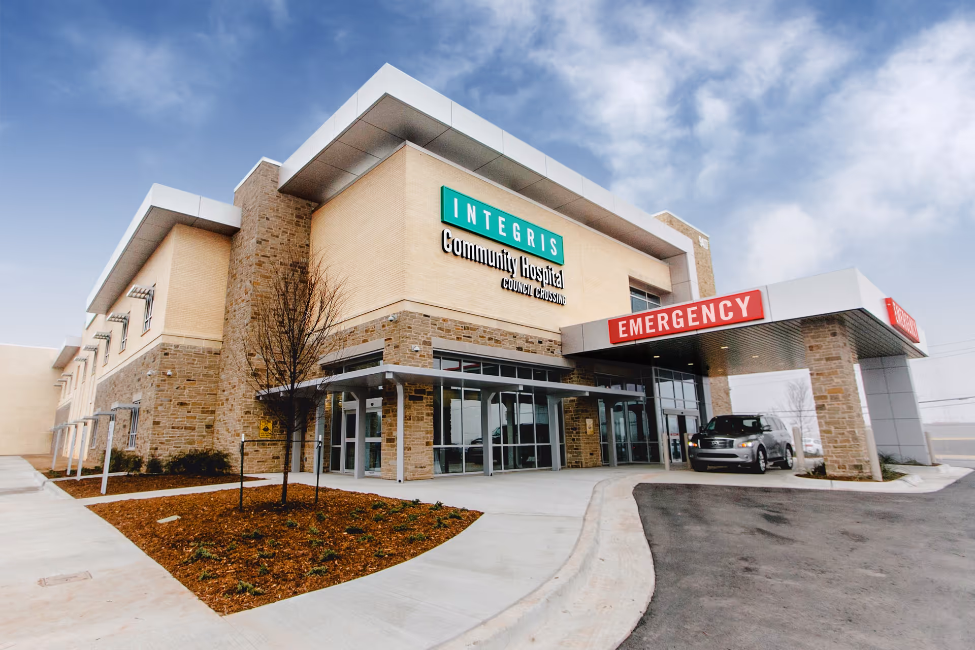 Exterior view of INTEGRIS Health Community Hospital, Council Crossing, with entrance and emergency sign.
