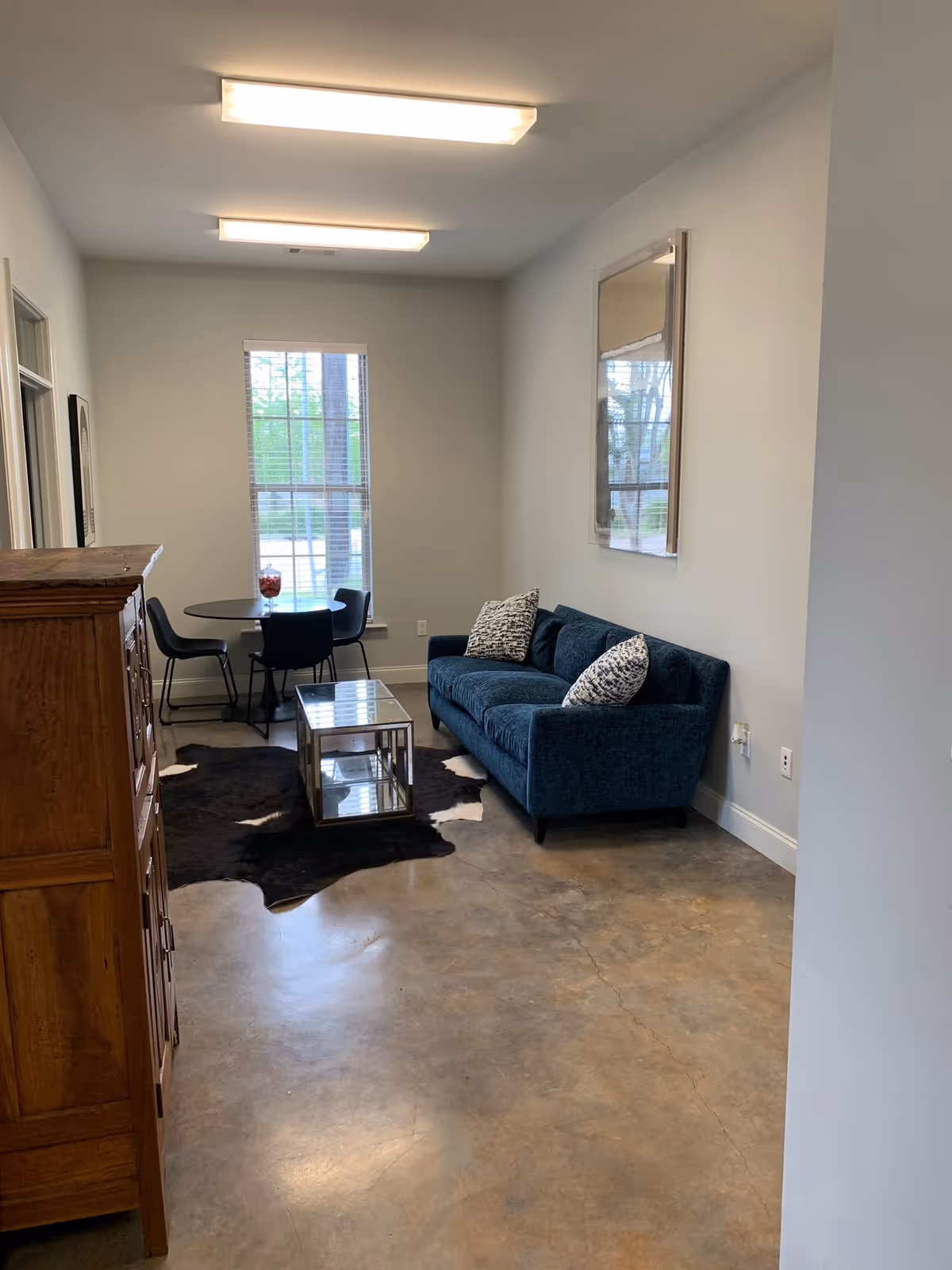 Interior common area featuring a blue sofa, coffee table, rug, and small dining table.