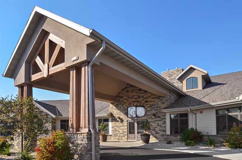 Front entrance of Canterbury Arms Assisted Living featuring a stone façade and wooden archway.