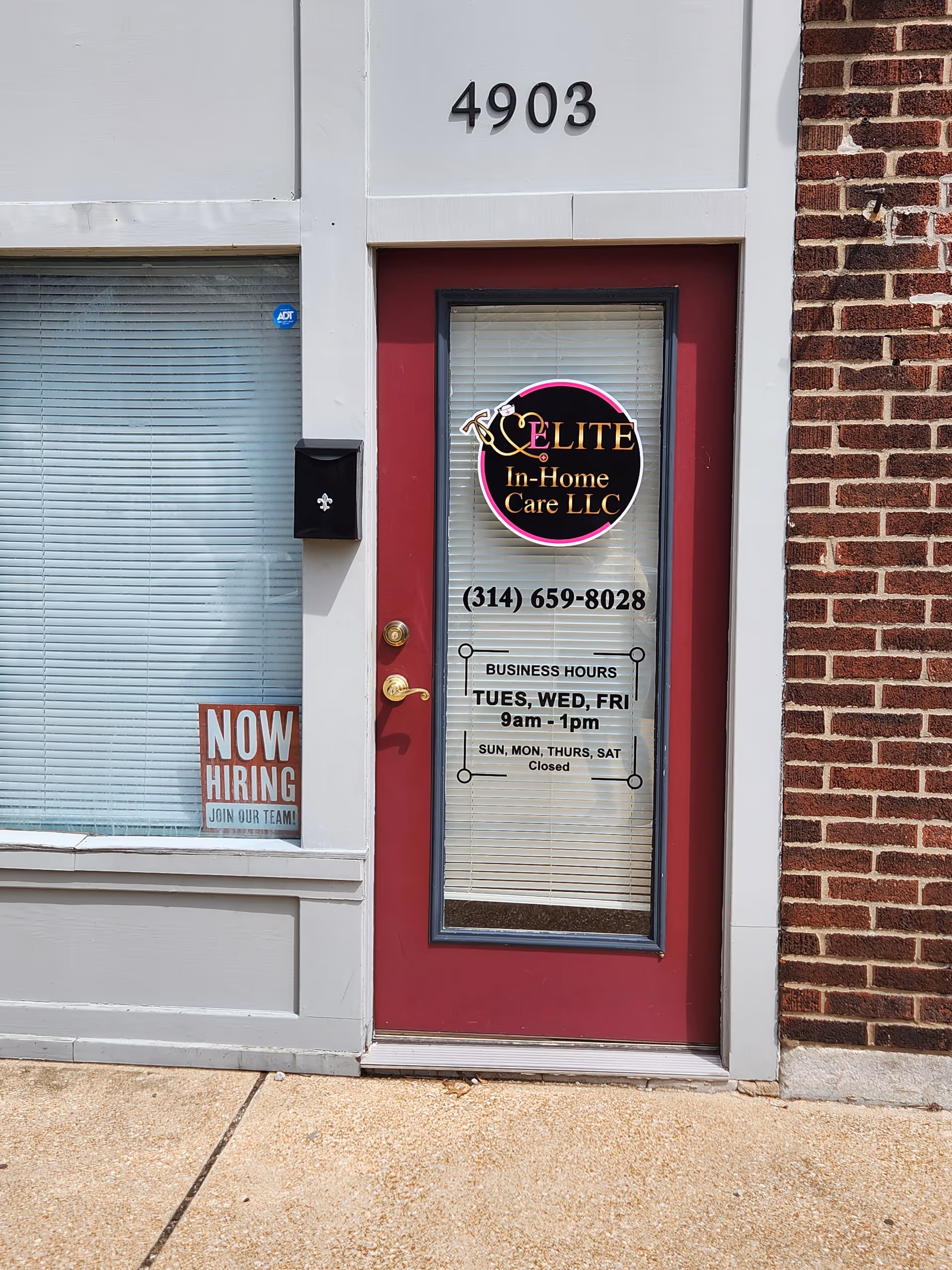 Storefront with red door, Elite In-Home Care logo, and a 'Now Hiring' sign.