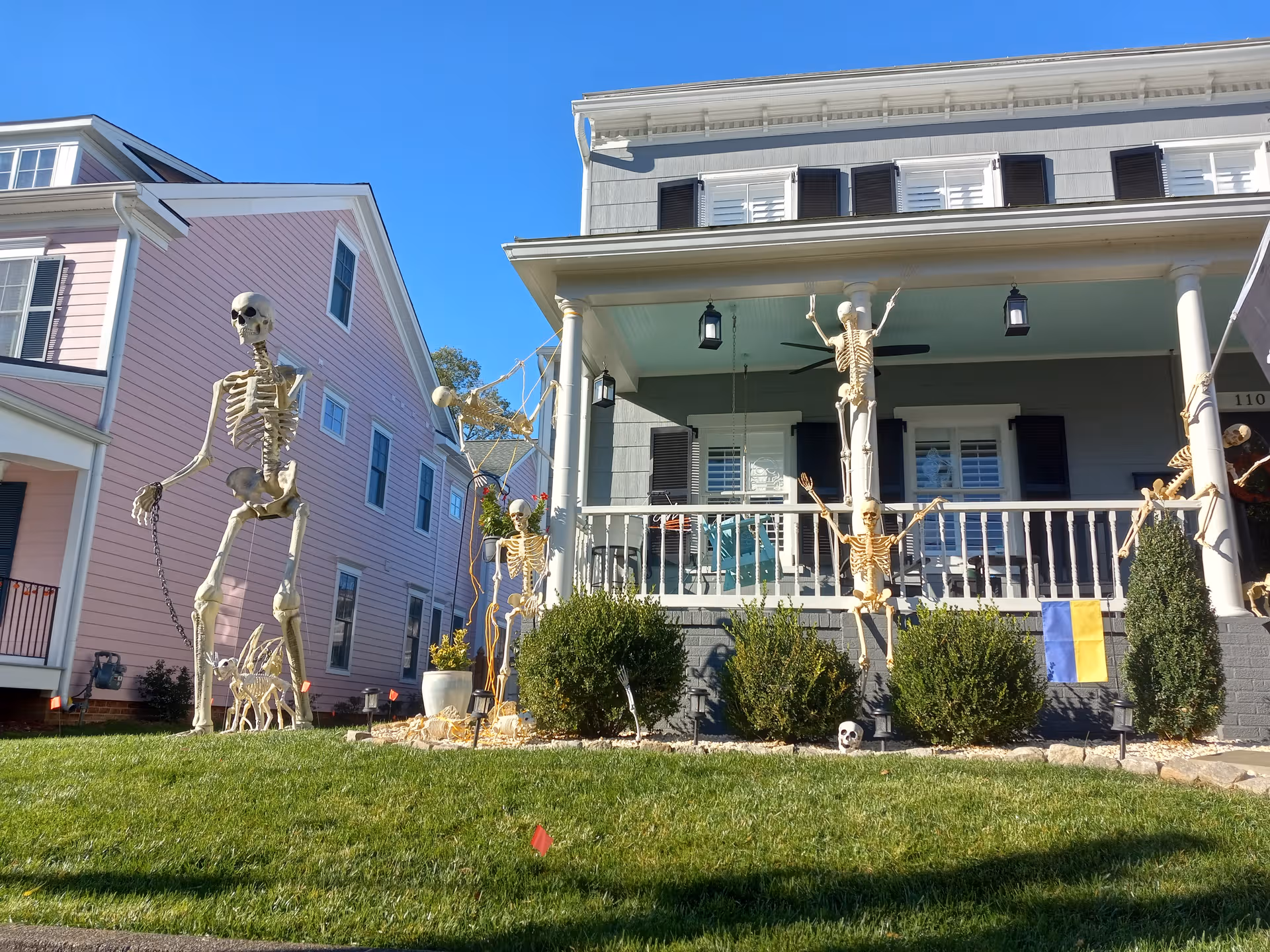 Front exterior of Hughes Home, Inc. with Halloween skeleton decorations along the lawn