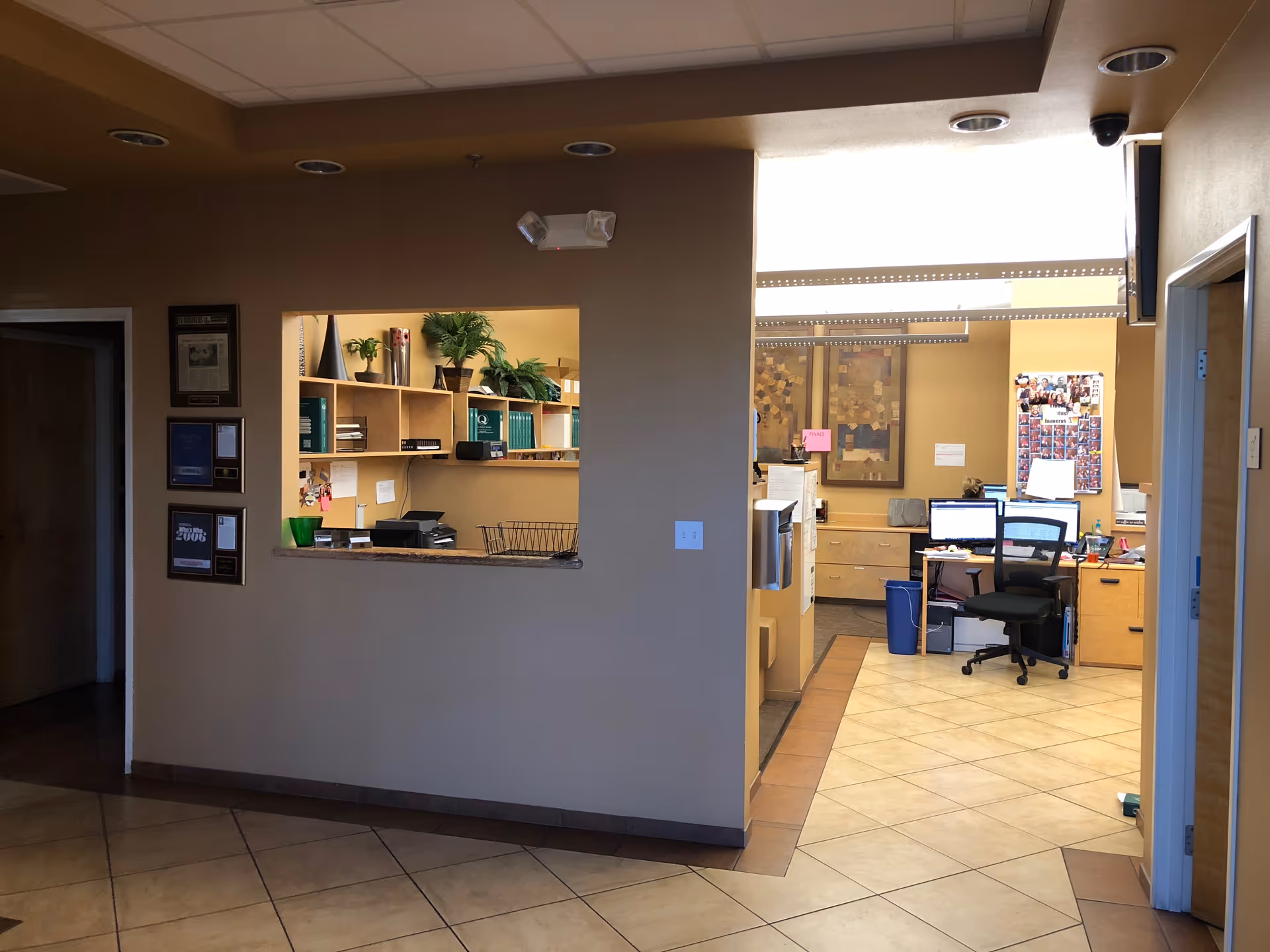 Interior reception area with windowed counter, shelves, and office desks.