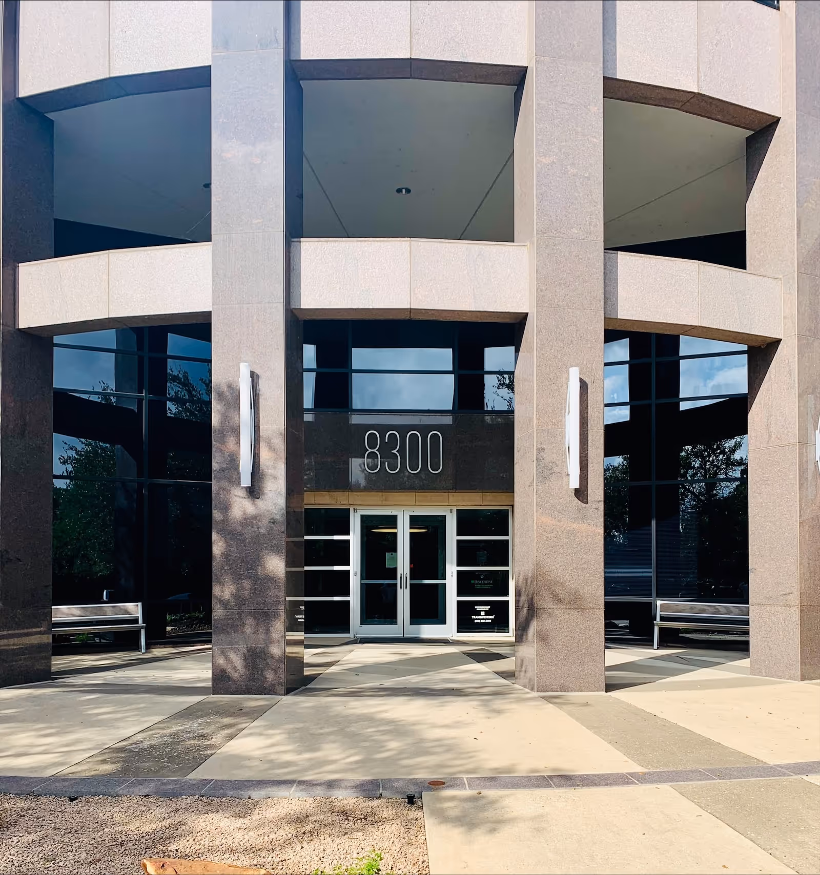 Modern stone-front building entrance with glass doors and address 8300.