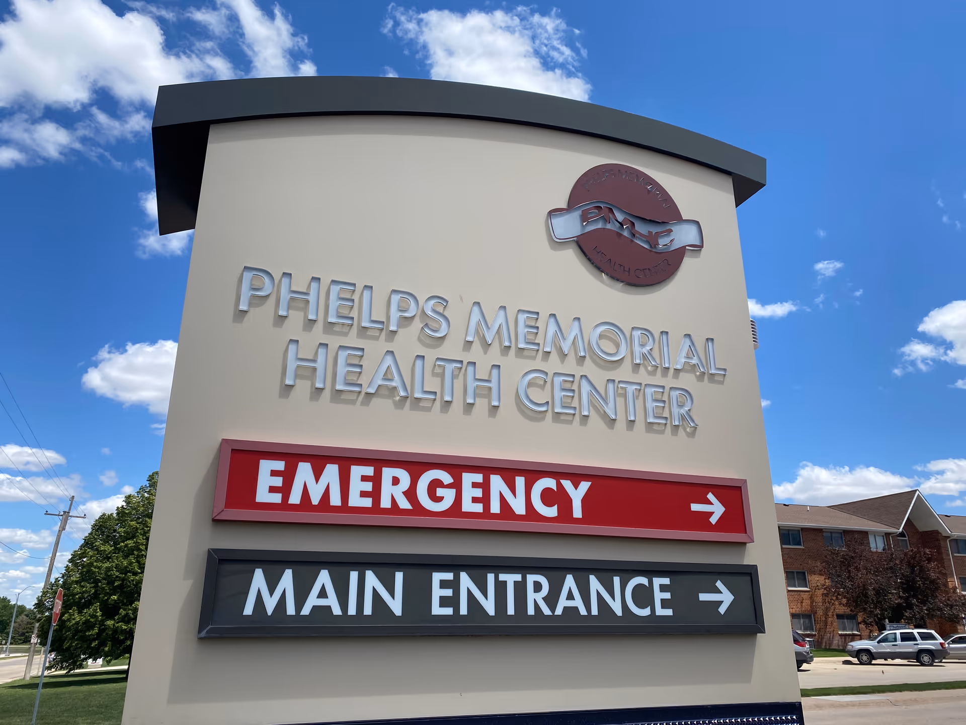 A tall beige sign displays Phelps Memorial Health Center with emergency and main entrance arrows.