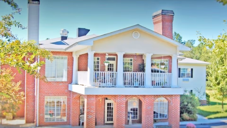 Two-story brick Hamilton Place senior living facility with white columns and balcony.