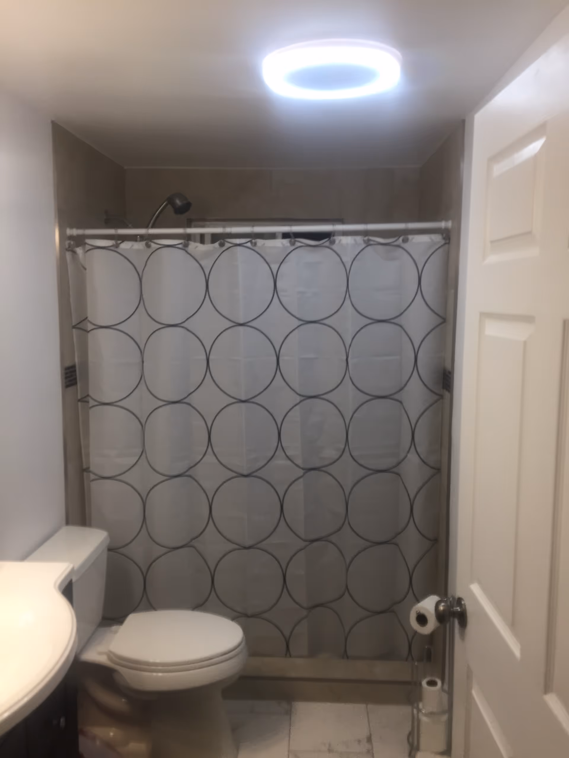 Small bathroom with toilet, sink, and shower curtain featuring circles.