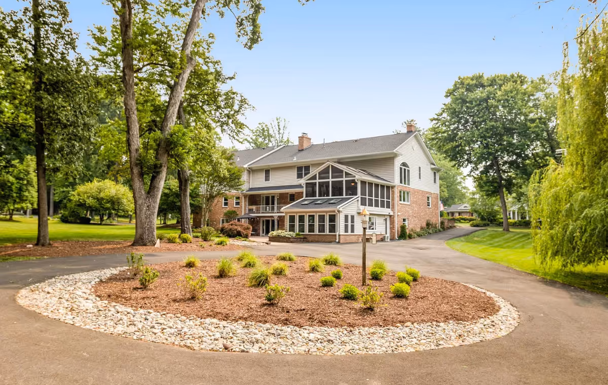 Two-story assisted living facility with circular gravel driveway and landscaped entrance.
