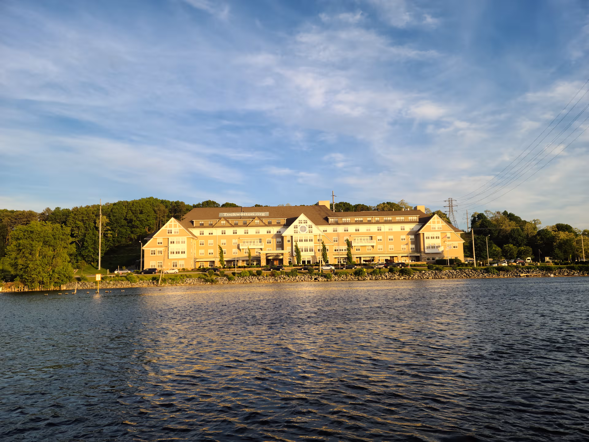 Waterfront senior living facility building viewed from across a calm body of water.