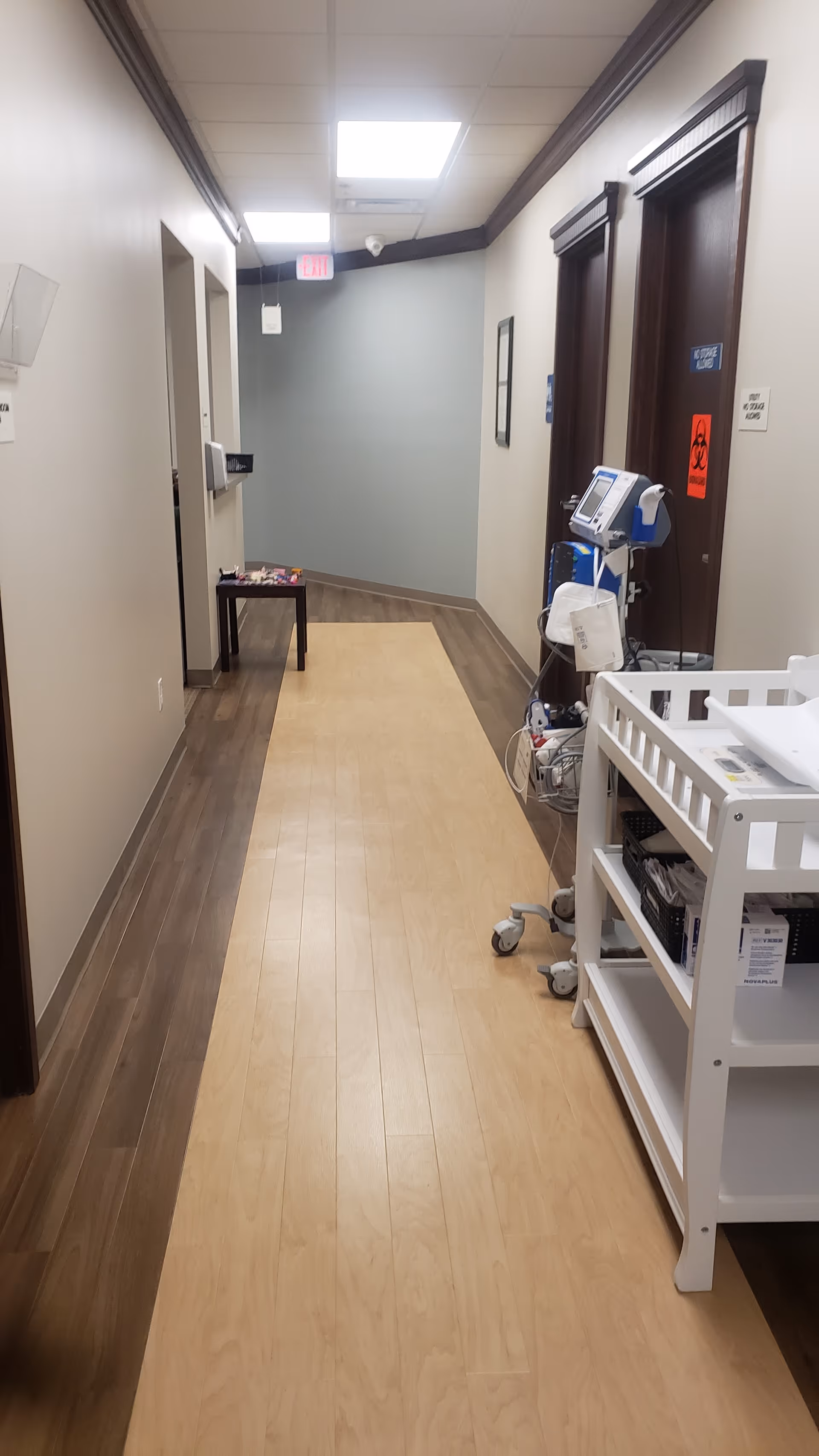 A hallway in Covenant Health Care with a medical cart, doors, and a bench.