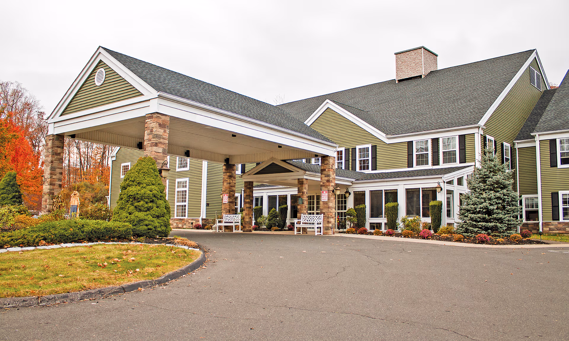 Senior living facility entrance with a porte-cochere and manicured landscaping.