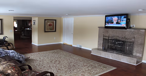 Cozy living room featuring a fireplace, wall-mounted TV, seating, and a patterned rug.