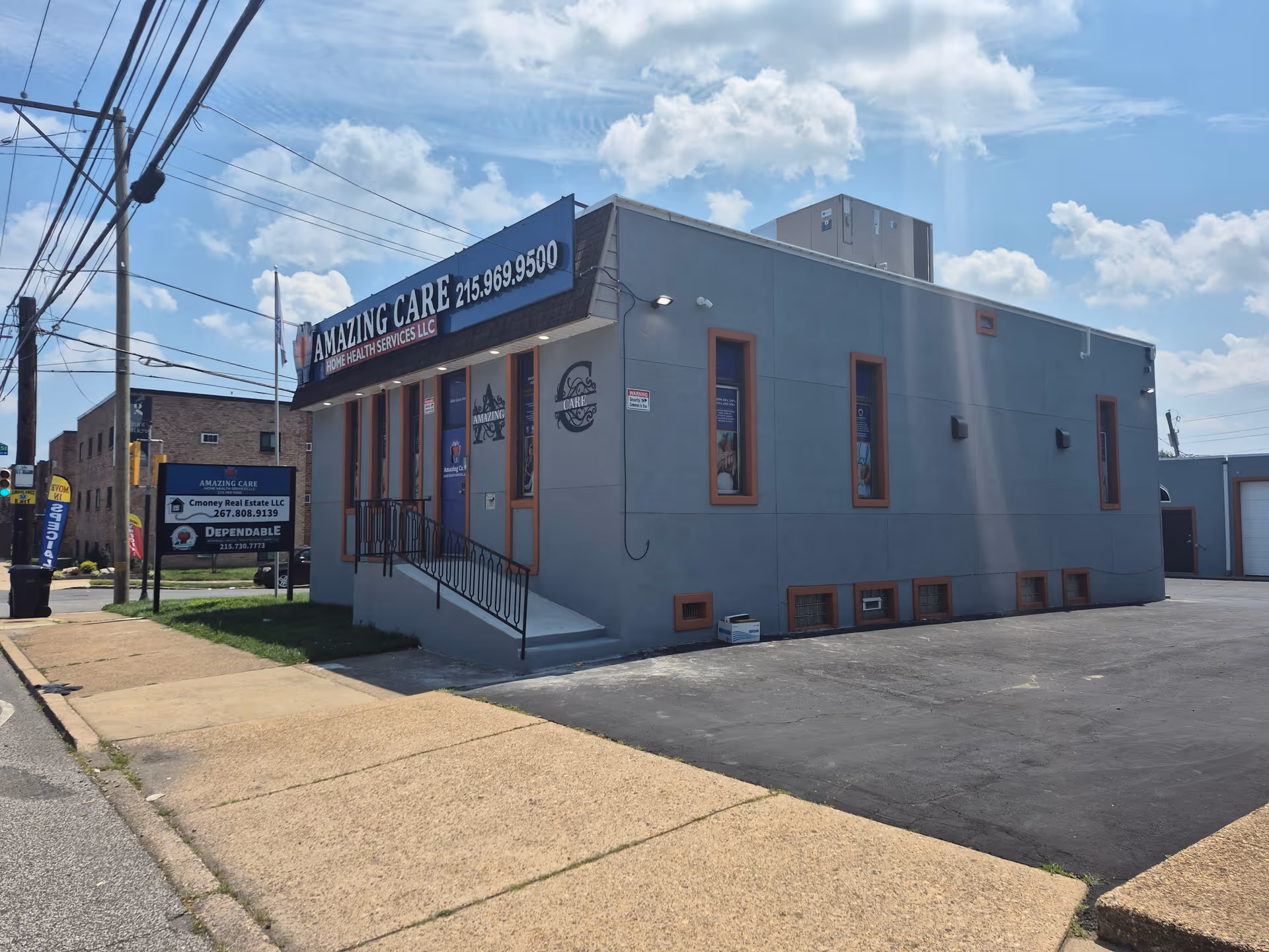 Blue-gray building with Amazing Care Home Health Services sign along a sunny street.