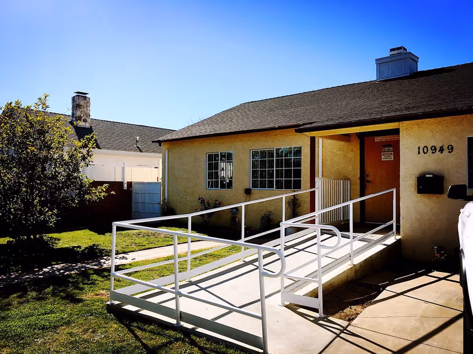 Exterior view of a single-story care facility with a wheelchair ramp to the entrance.