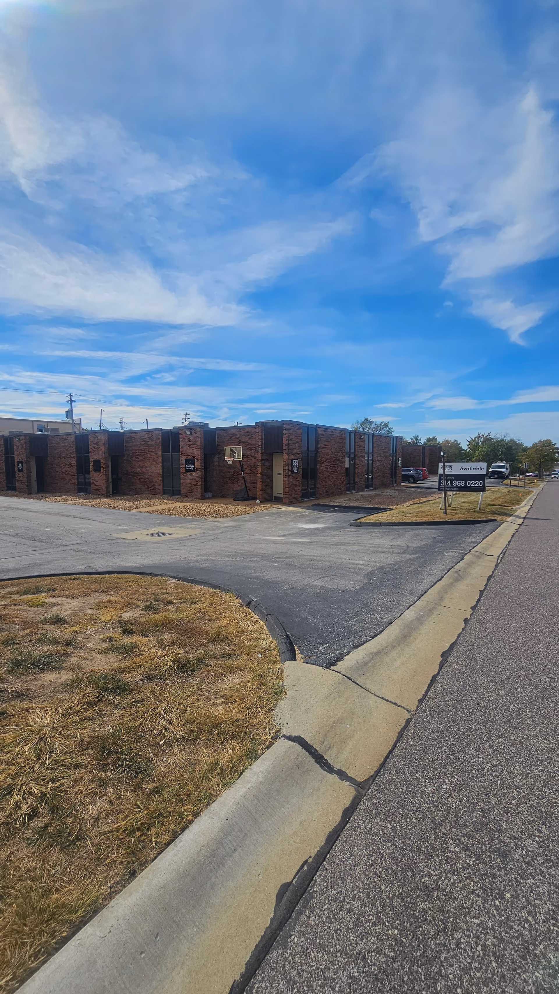 Exterior view of a brick building with a parking lot and sign