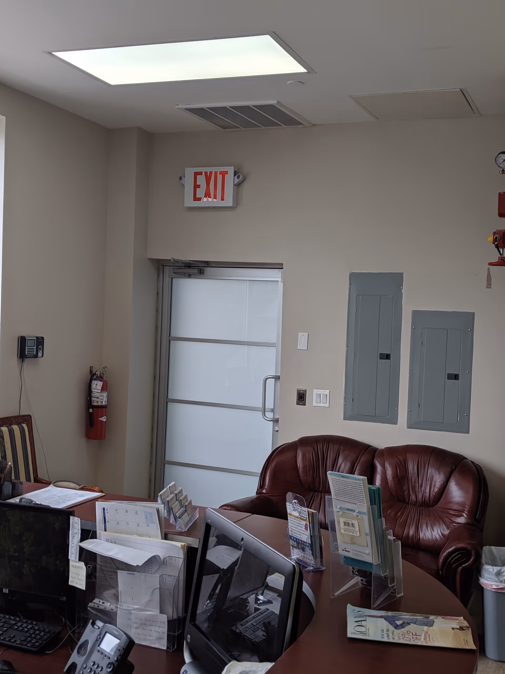 Interior reception area with desk, brochures, exit door, and a leather couch