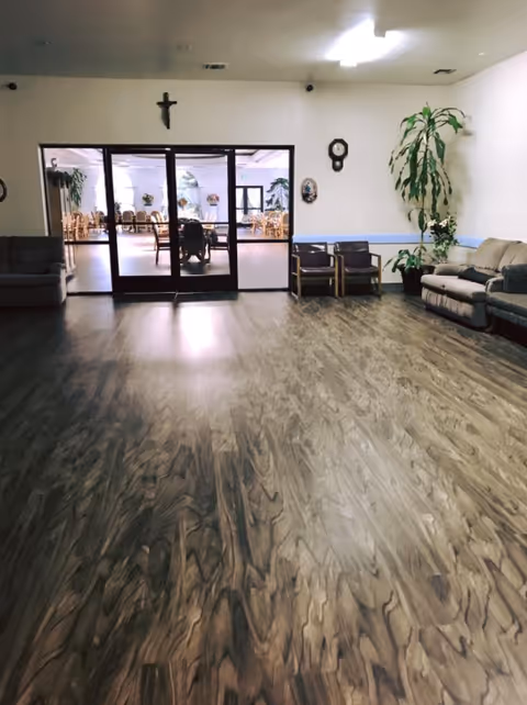 Interior lobby of St. Thomas Retirement Center with wooden floor, seating, and glass doors.